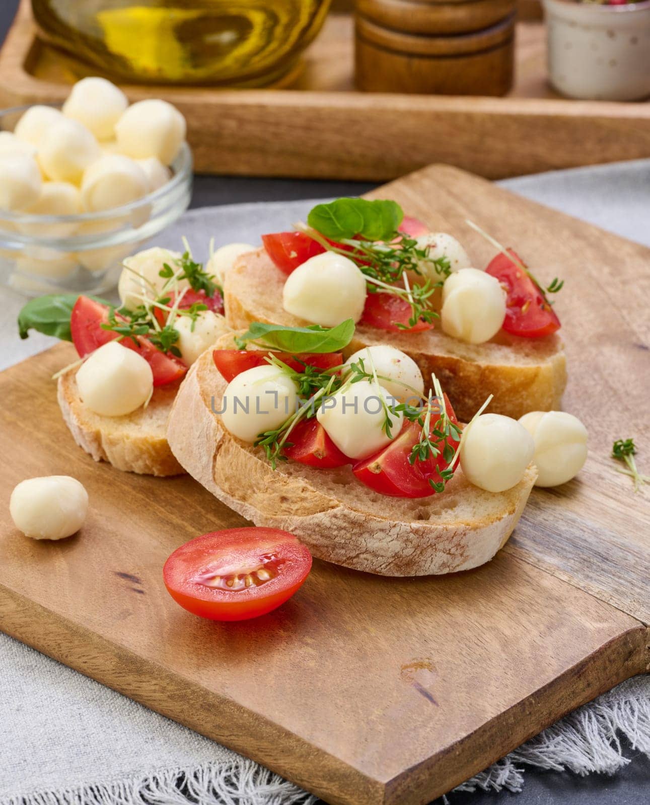 Round mozzarella, cherry tomatoes and microgreens on a piece of white bread, a healthy sandwich