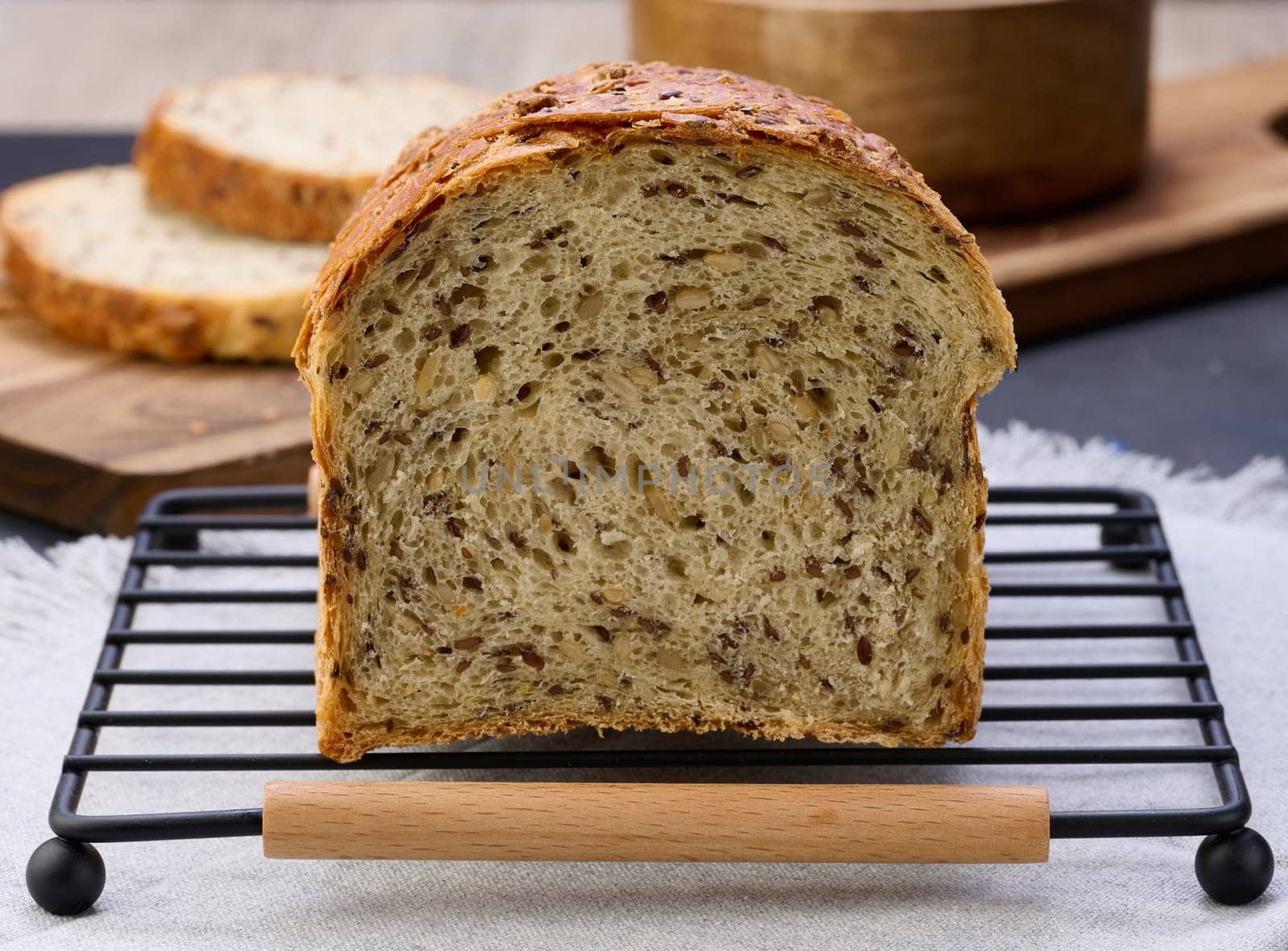 Sliced ​​white wheat flour bread with flax seeds on a wooden board, close up