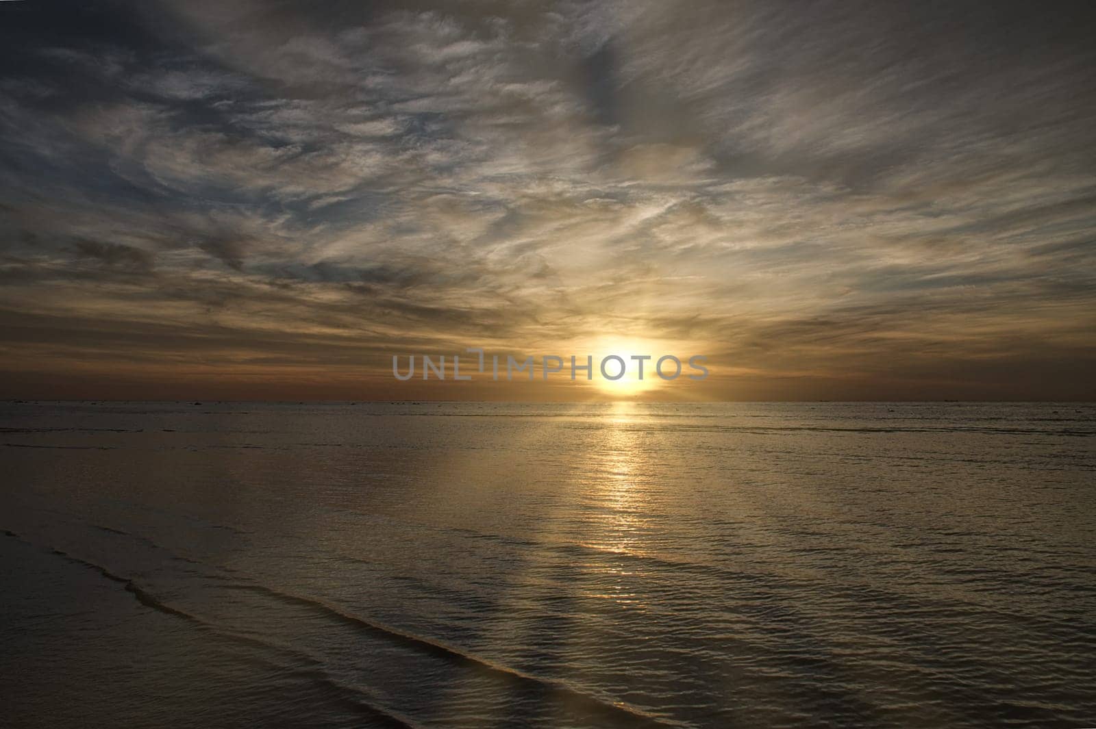 Sunset on the beach by the sea. Gentle waves. Sparkling water. The island of Poel on the Baltic Sea. Nature photo from the coast