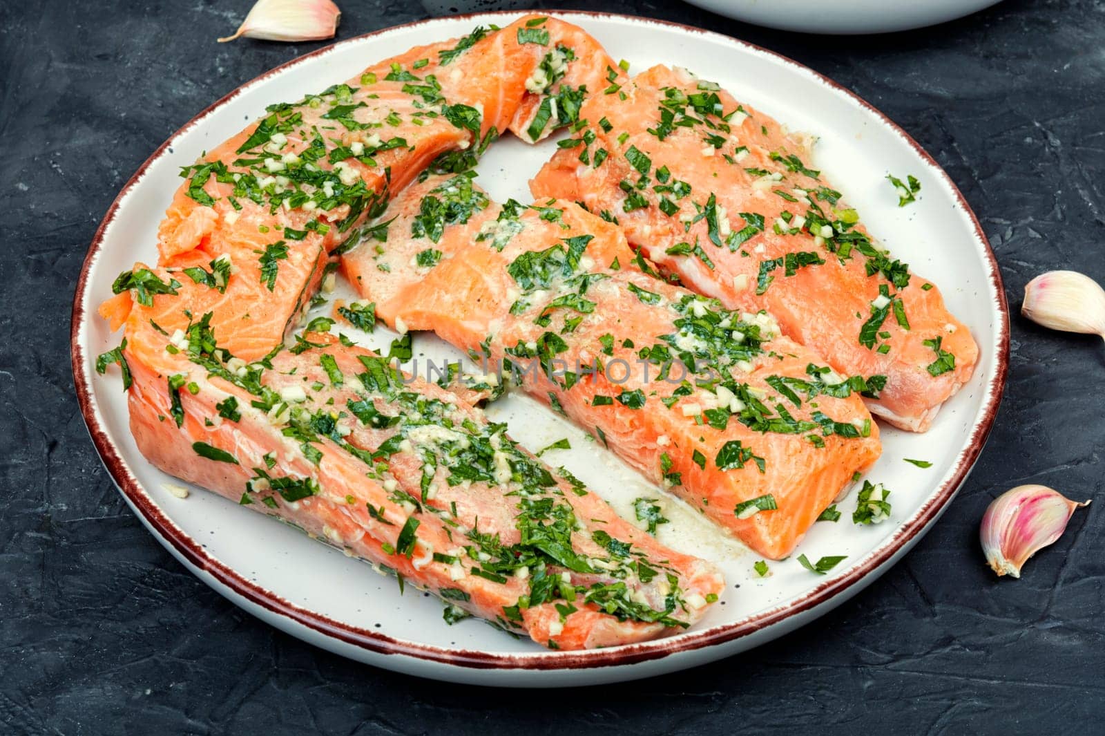 Raw uncooked salmon or trout fillet fish in garlic green marinade.