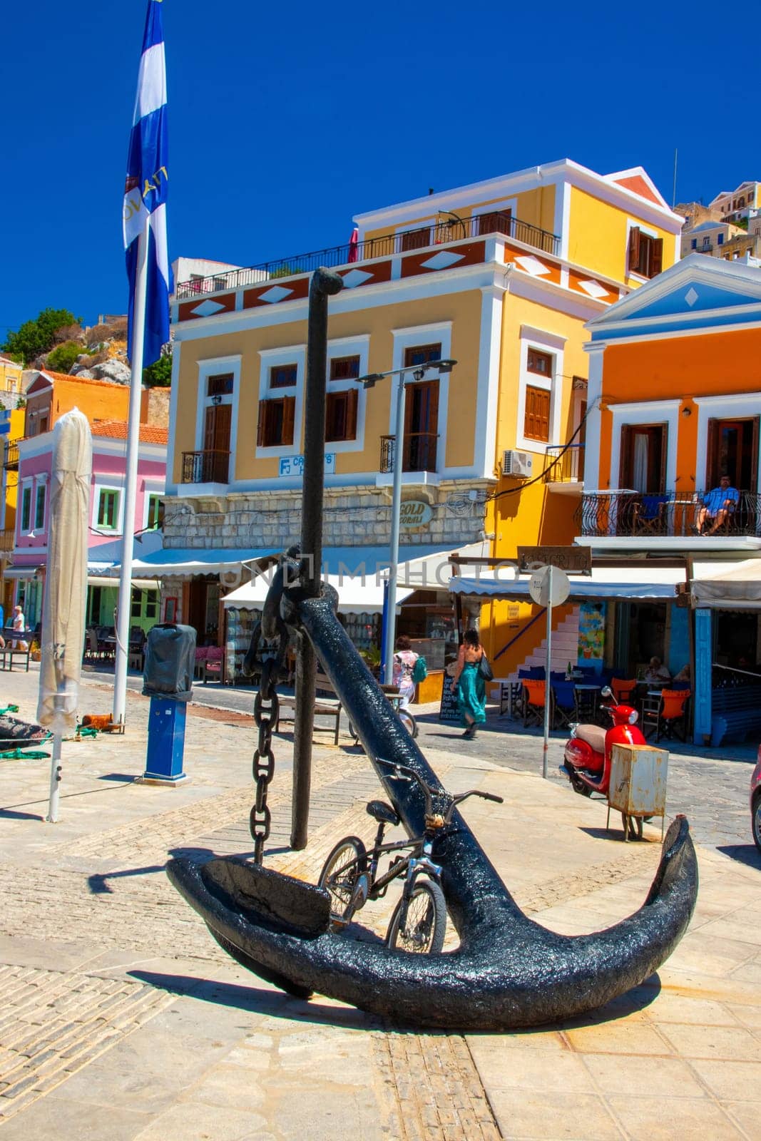 SYMI, Greece - 03 JUNE 2021. A old big Anchor sculpture on Symi town promenade on the pictorial port of Symi island in Greece. Dodecanese.