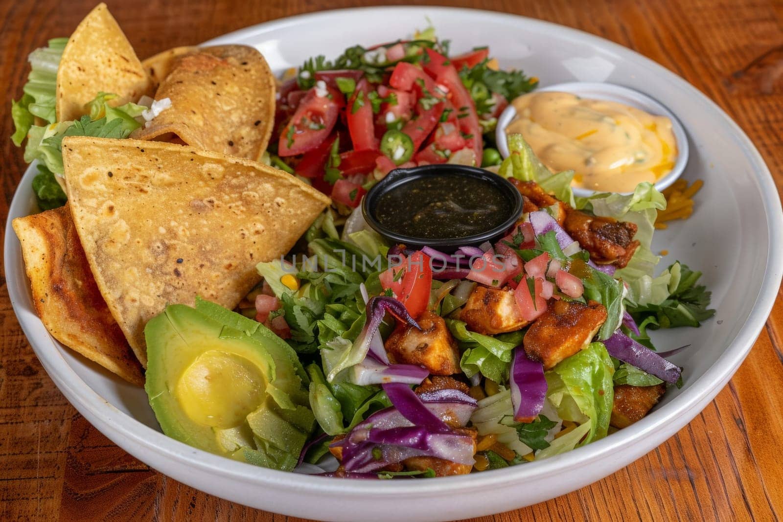A white bowl brimming with a vibrant salad next to crunchy tortilla chips, creating a playful and colorful food composition.