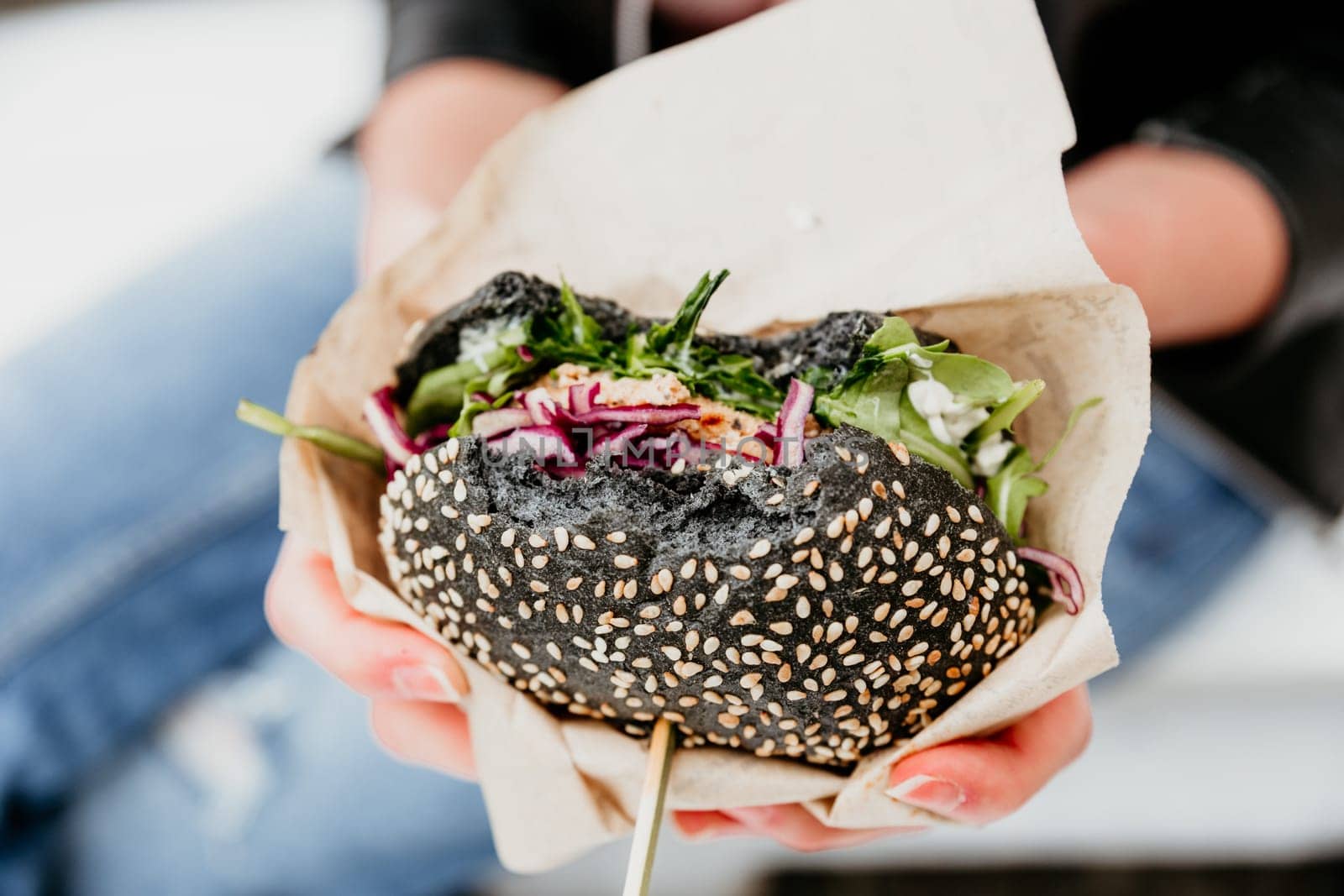 Close up of woman hands holding delicious organic salmon vegetarian burger on open air beer an burger urban street food festival in Ljubljana, Slovenia