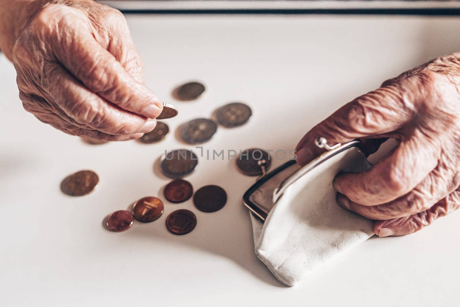 Detailed closeup photo of elderly 96 years old womans hands counting remaining coins from pension in her wallet after paying bills. Unsustainability of social transfers and pension system.