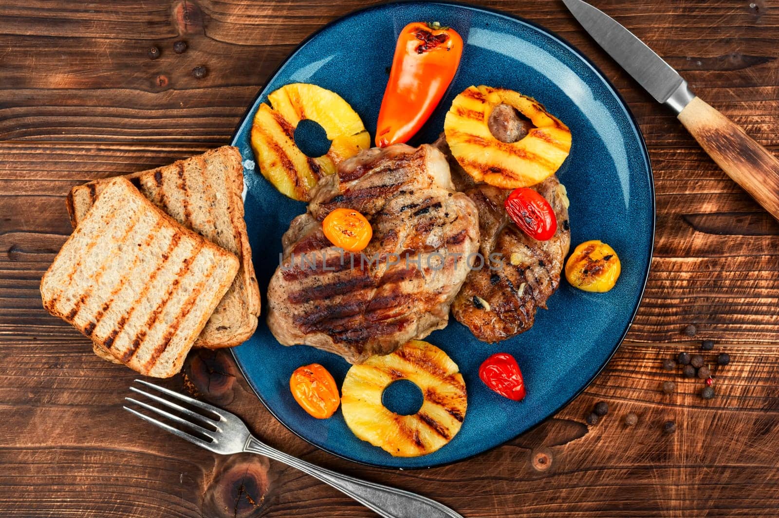 Tasty grilled meat,roasted with pineapple. Grilled steak and ananas on wooden table.