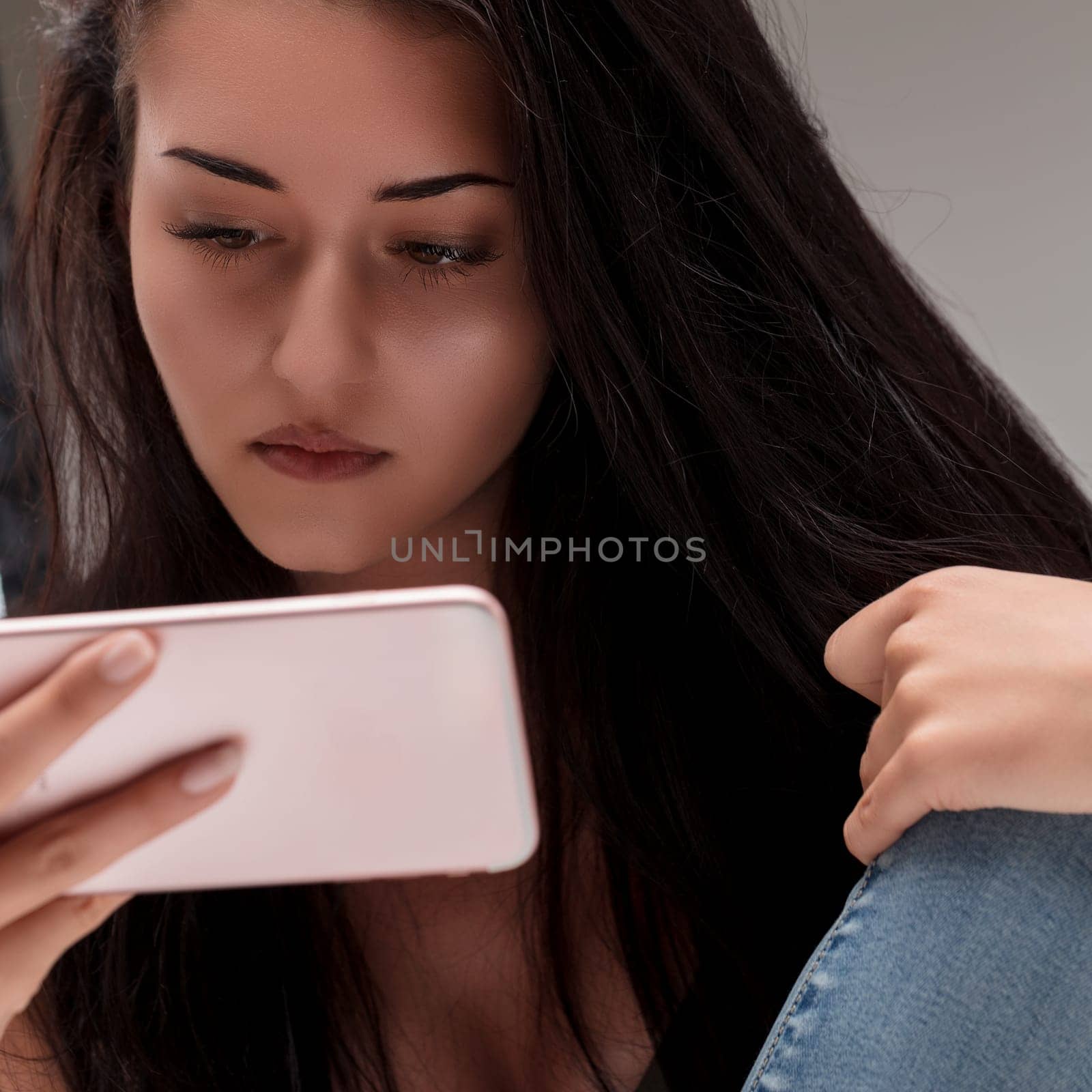 Young woman's gaze is fixed on her phone, reflecting a moment of personal reflection and digital interaction