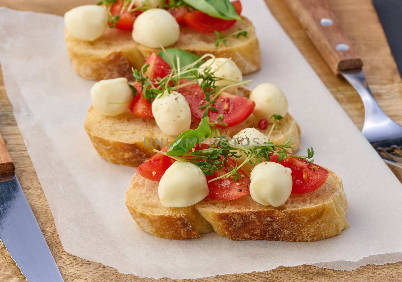 Round mozzarella, cherry tomatoes and microgreens on a piece of white bread, a healthy sandwich