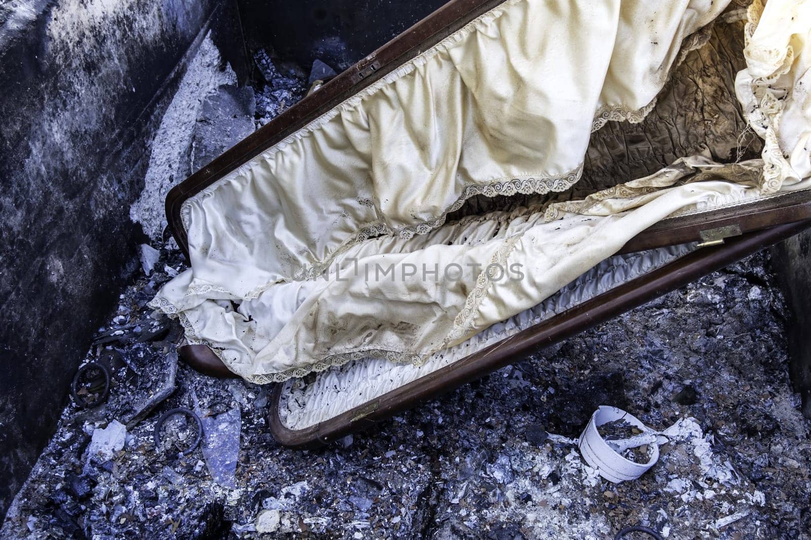 Burnt coffin wit0h flowers in cemetery, religion and burial