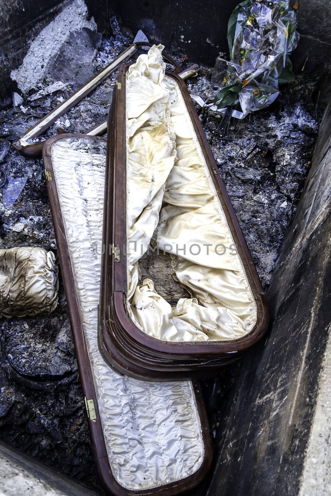 Burnt coffin wit0h flowers in cemetery, religion and burial