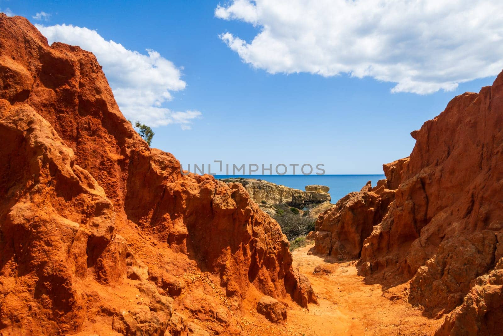Amazing red sandstone rocks of the coastal cliffs, steep coast near Praia dos Paradinha, Albufeira, Algarve, Portugal