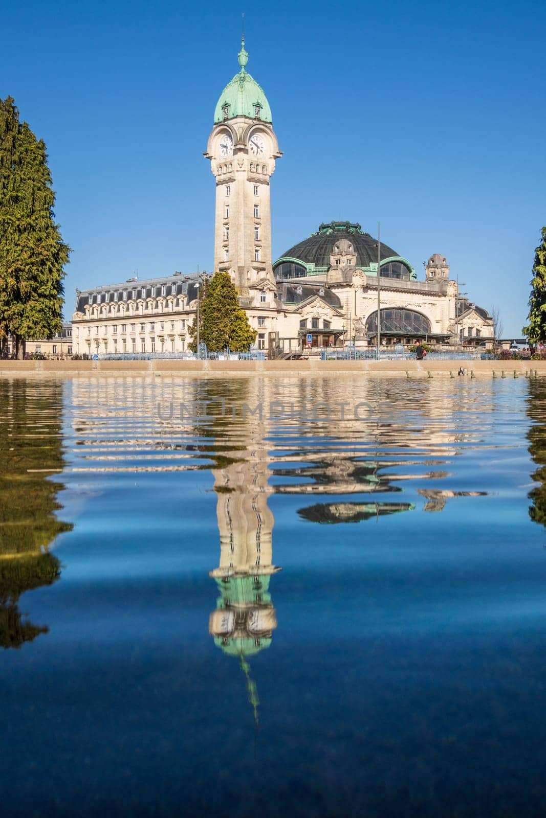 Limoges, France - April 04 2023: View of the famous Limoges train station called Limoges-Bénédictins reflecting in water, in France. vertical photography