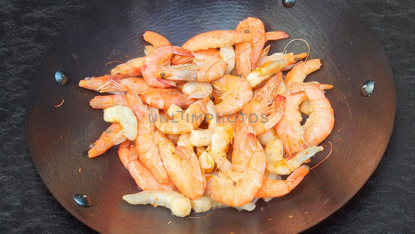 Fry shrimps in a pan with herbs and garlic. on dark background. View from above