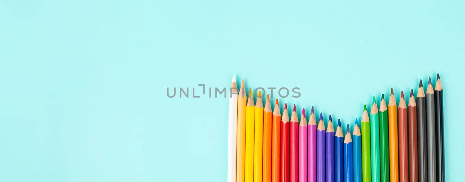 Color pencils collection in a row, back to school, drawing supplies, blue background with copy space