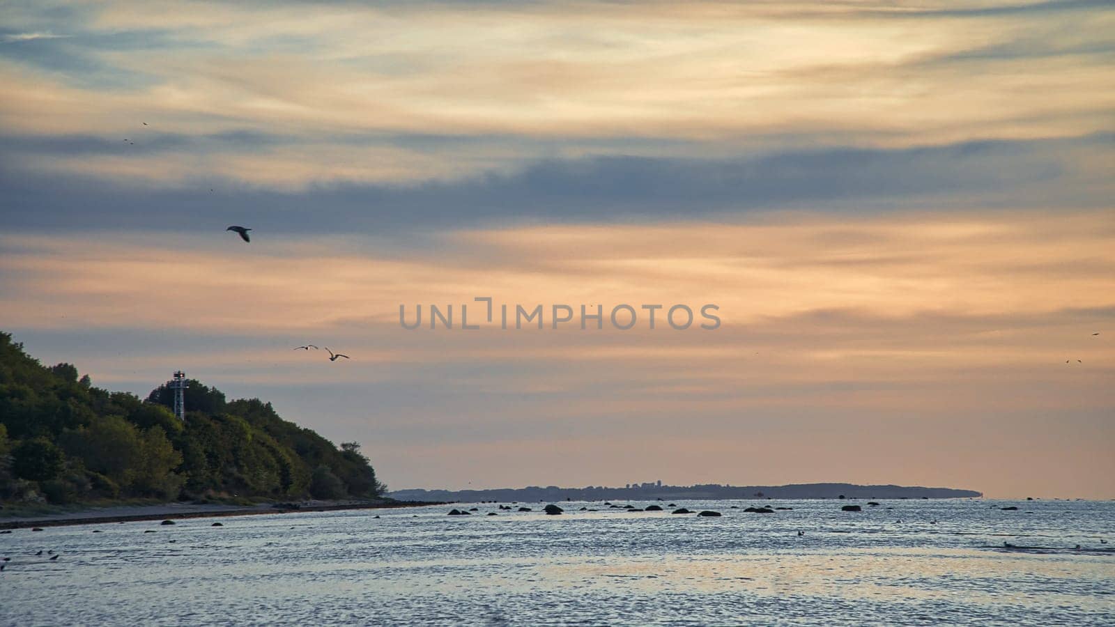 Sunset, illuminated sea. Sandy beach in the foreground. Light waves. Poel island on the Baltic Sea. Nature photo from the coast