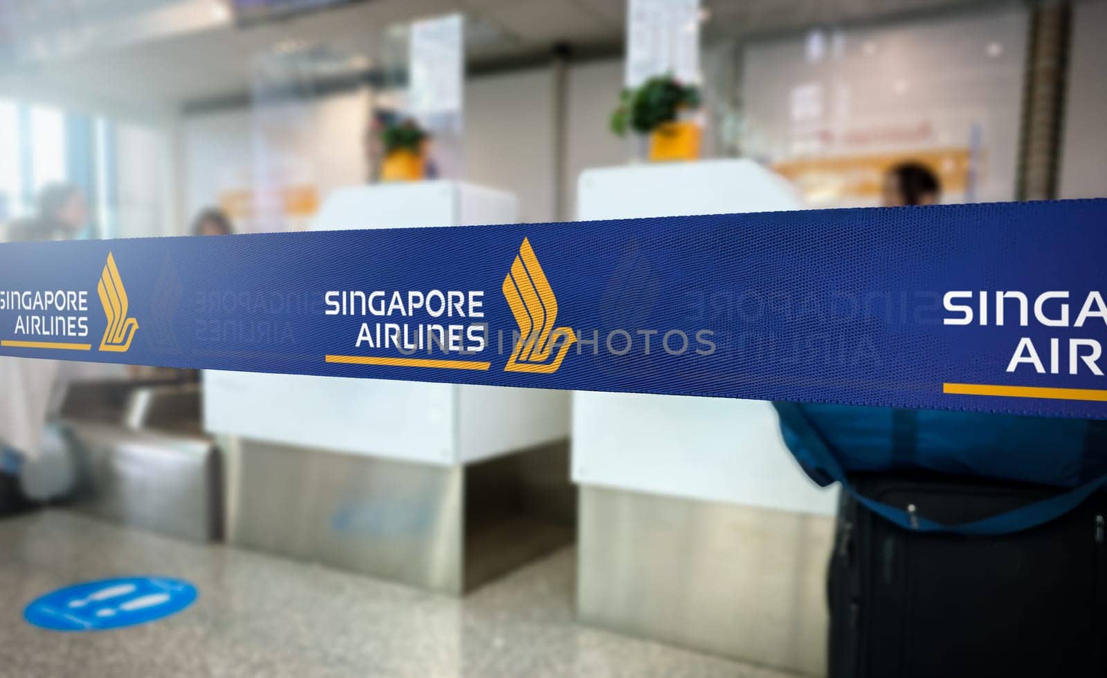 Singapore, SG, May 14 2024  Close-up of the check-in area at an airport featuring the blue ribbon with the golden logo of Singapore Airlines, illustrating the airline’s presence and branding.