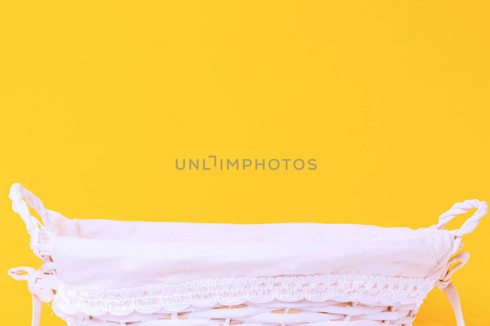 Empty wicker basket over light yellow background. For your food and product display assembly. Macro of a white straw basket. Copy space.