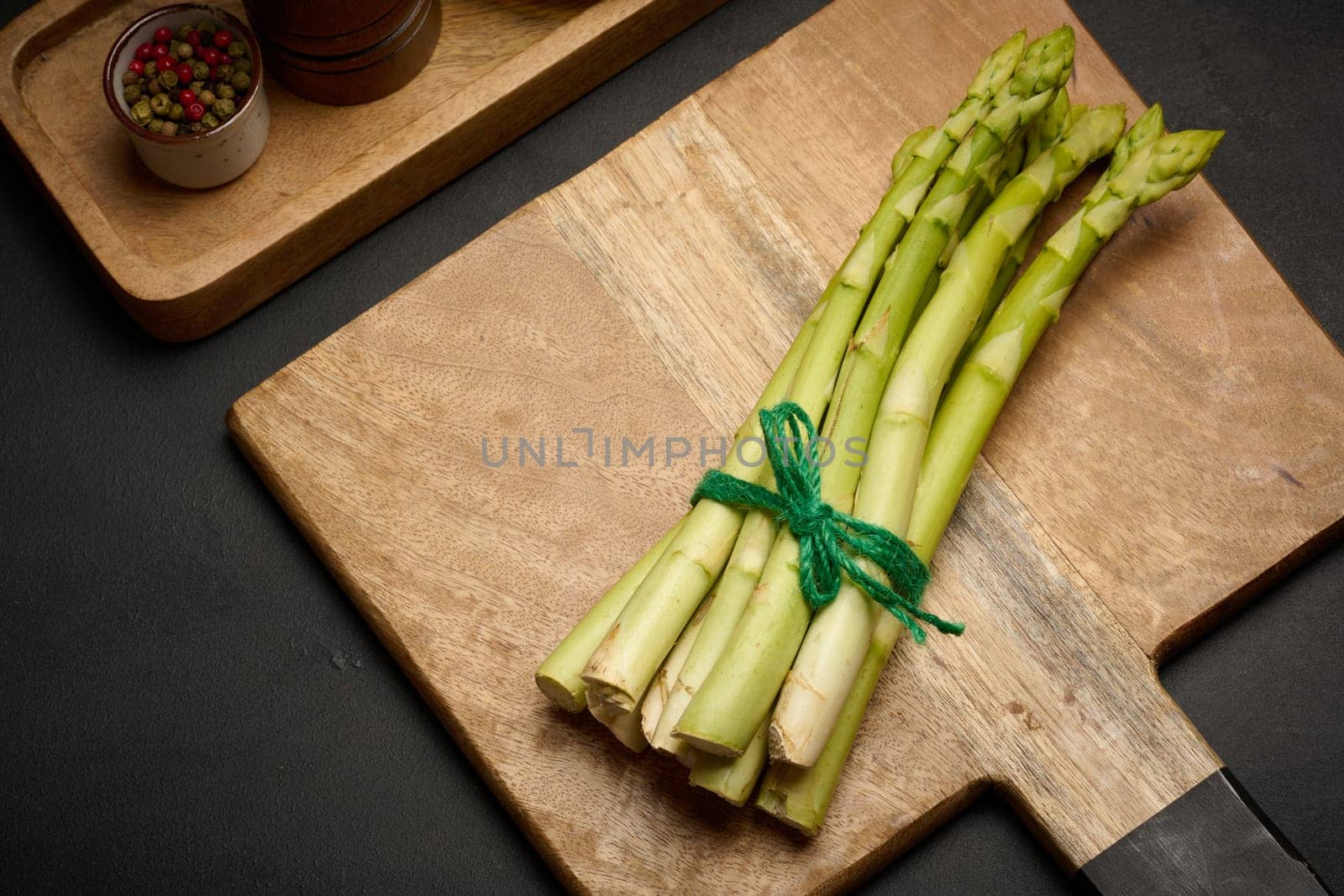 Fresh green asparagus sprouts on a black wooden background. View from above