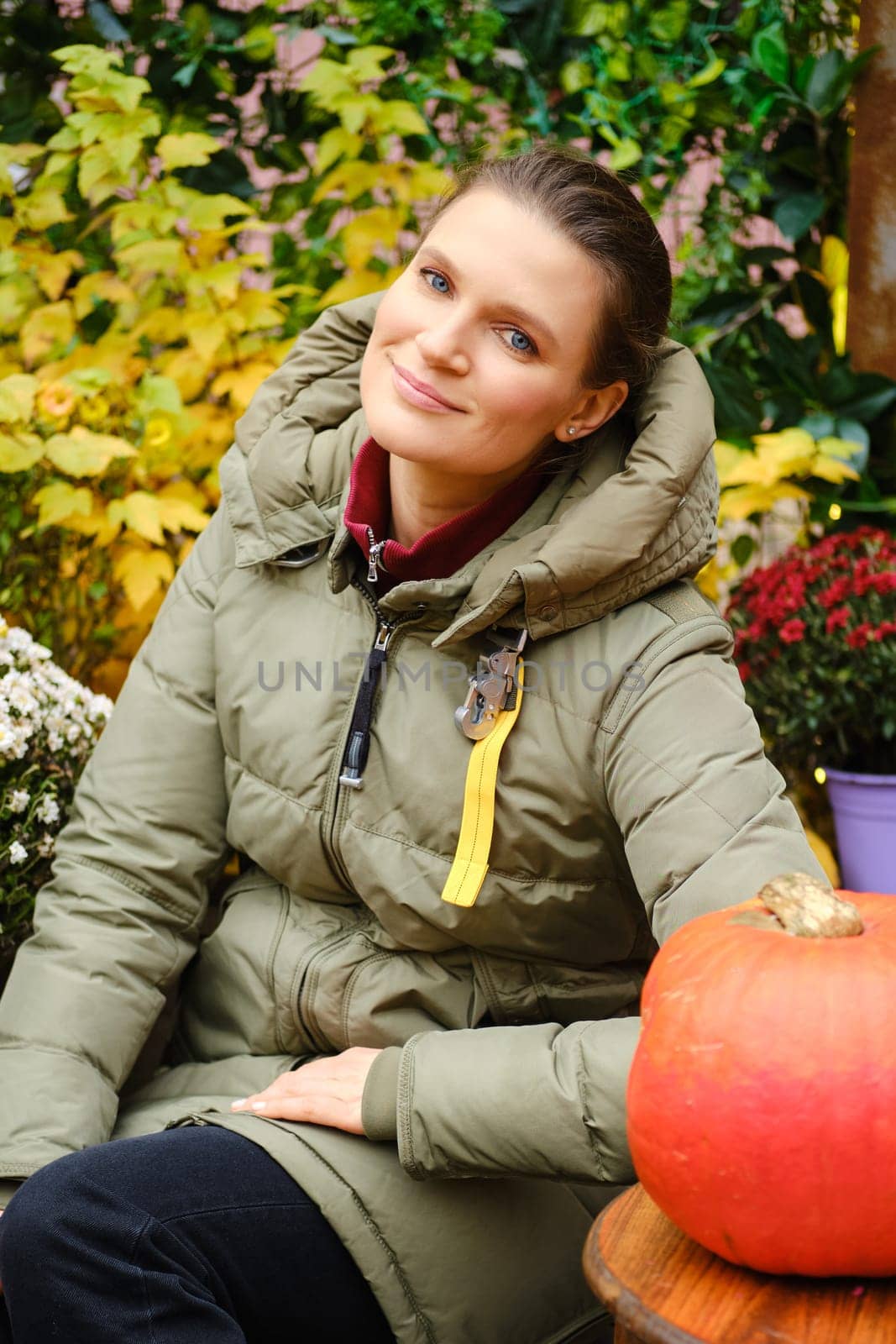 Outdoor portrait of pretty mid age woman surrounded with autumn flowers