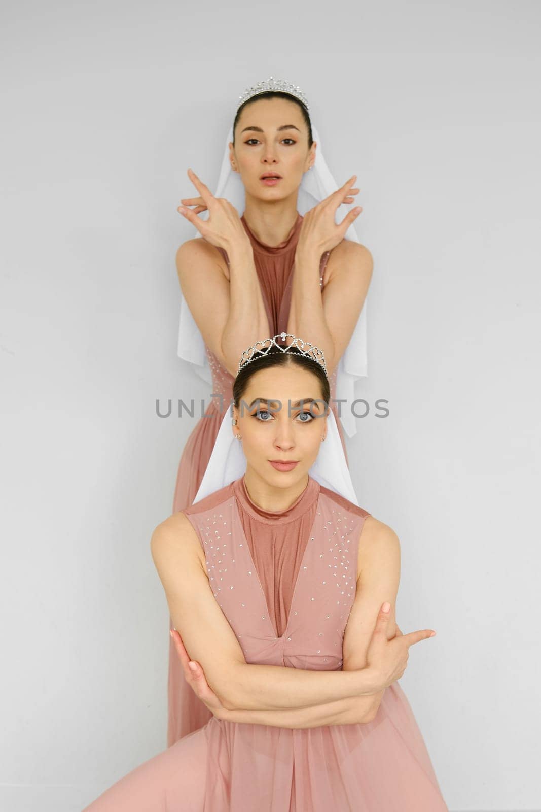 Ballerinas stand one after another and perform hand movements over grey background