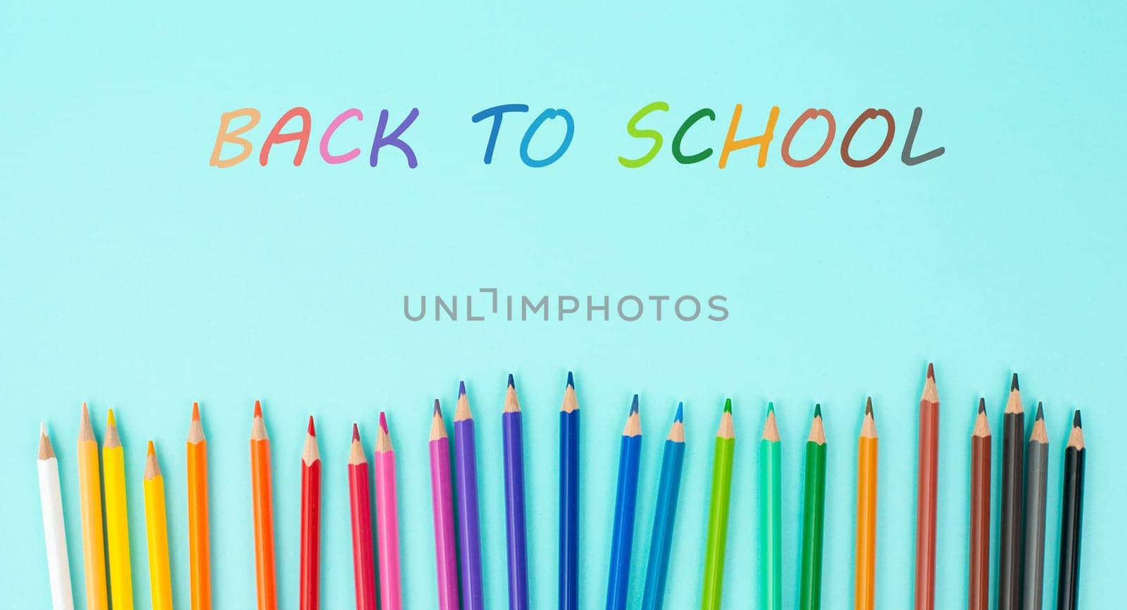 Color pencils collection in a row, back to school, drawing supplies, blue background with copy space