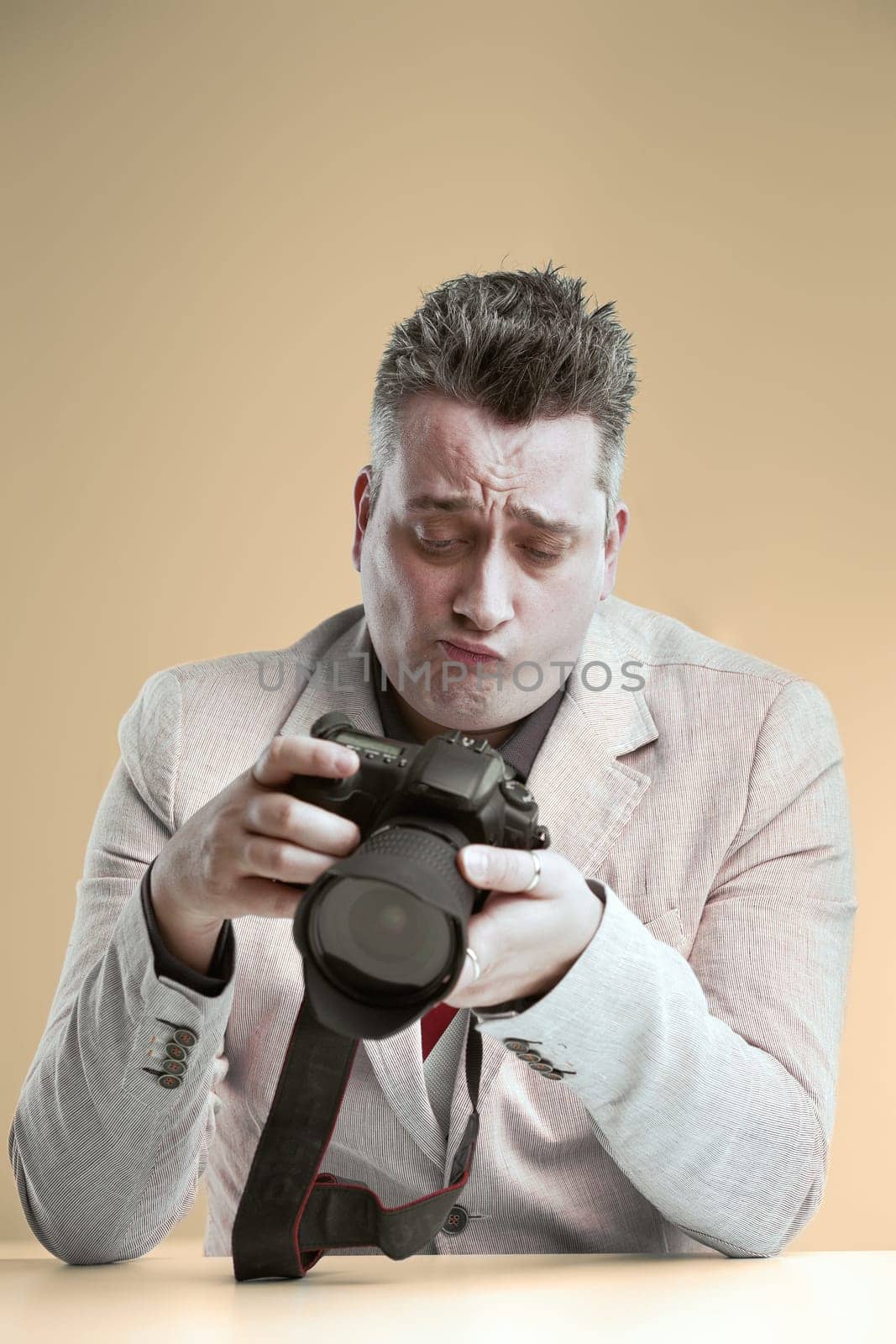 Critical photographer examines his camera with a meticulous eye, analyzing every detail with a critical frown