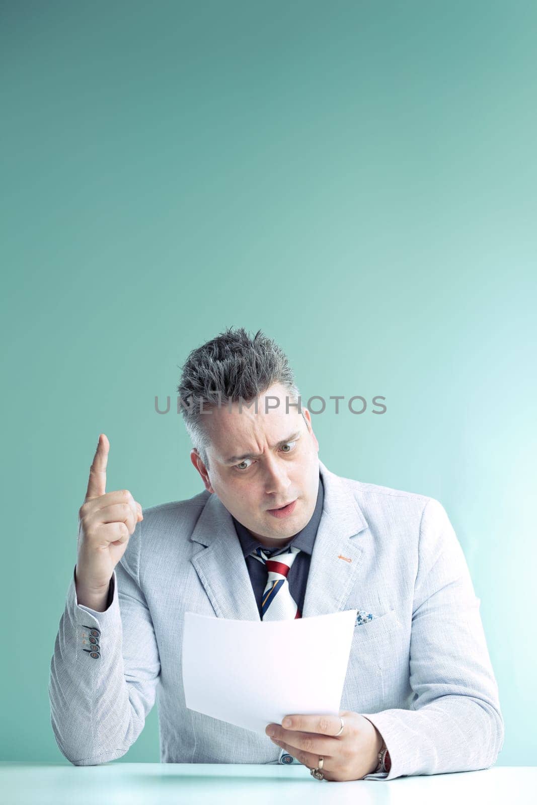 Engaged anchorman in light grey suit gestures emphatically while holding papers, his expression one of urgent revelation