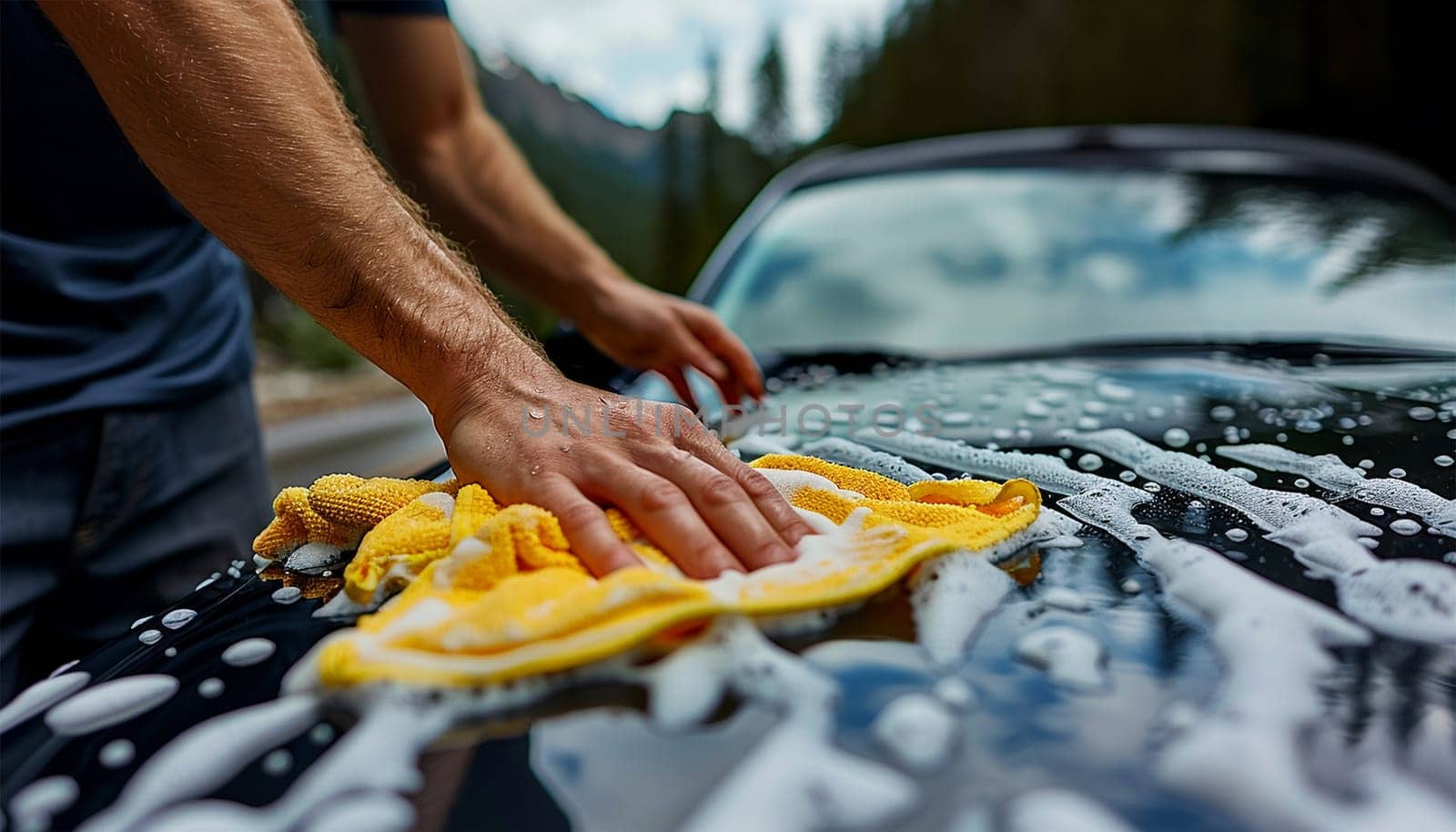 Close-up of car washing process. Unknown man washing his car outside. at the rear wheel of his car, washes the vehicle in the backyard of the house. Car cleaning concept. People and transport Close up