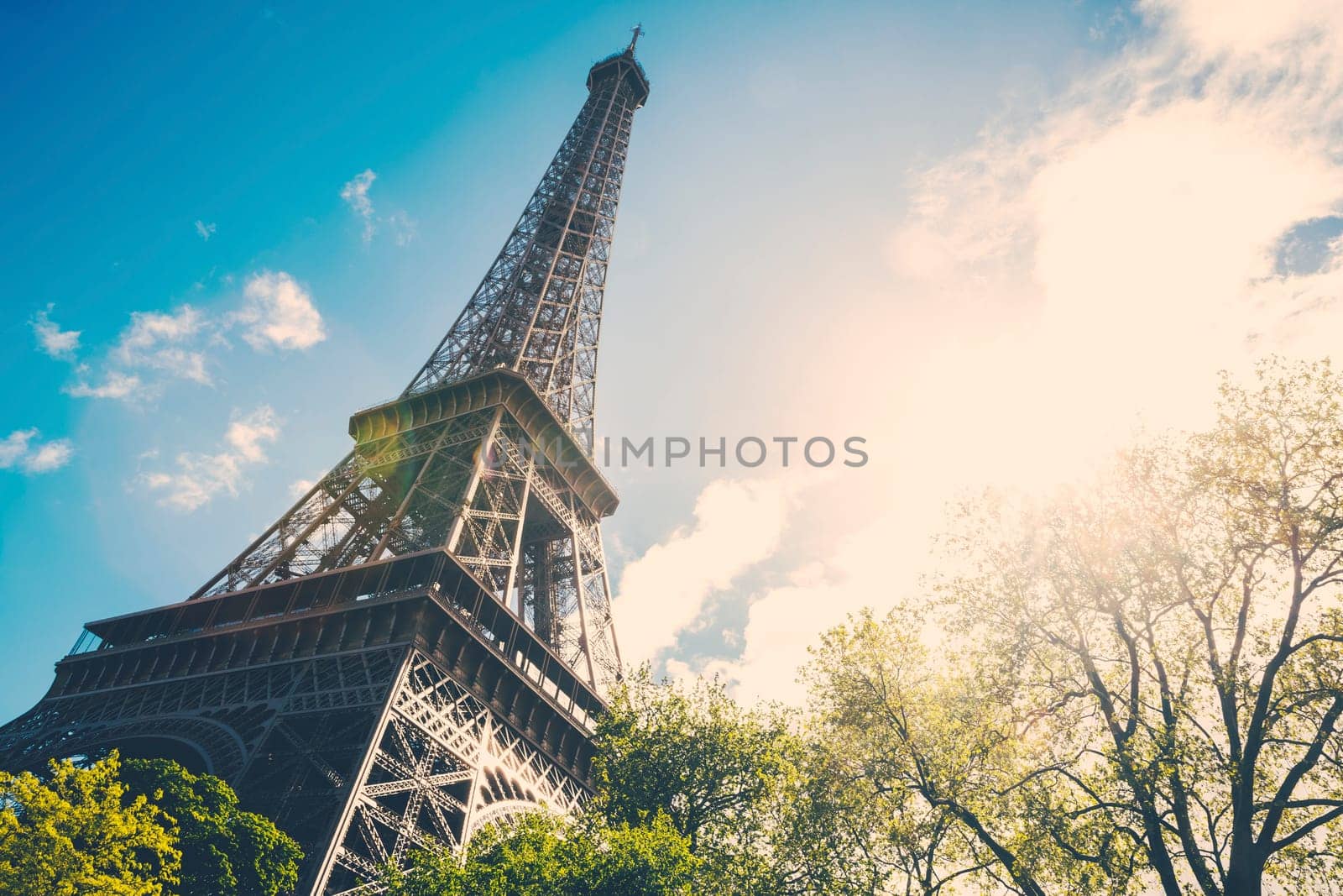 The Eiffel Tower in Paris, France during the morning with a strong lens flare.