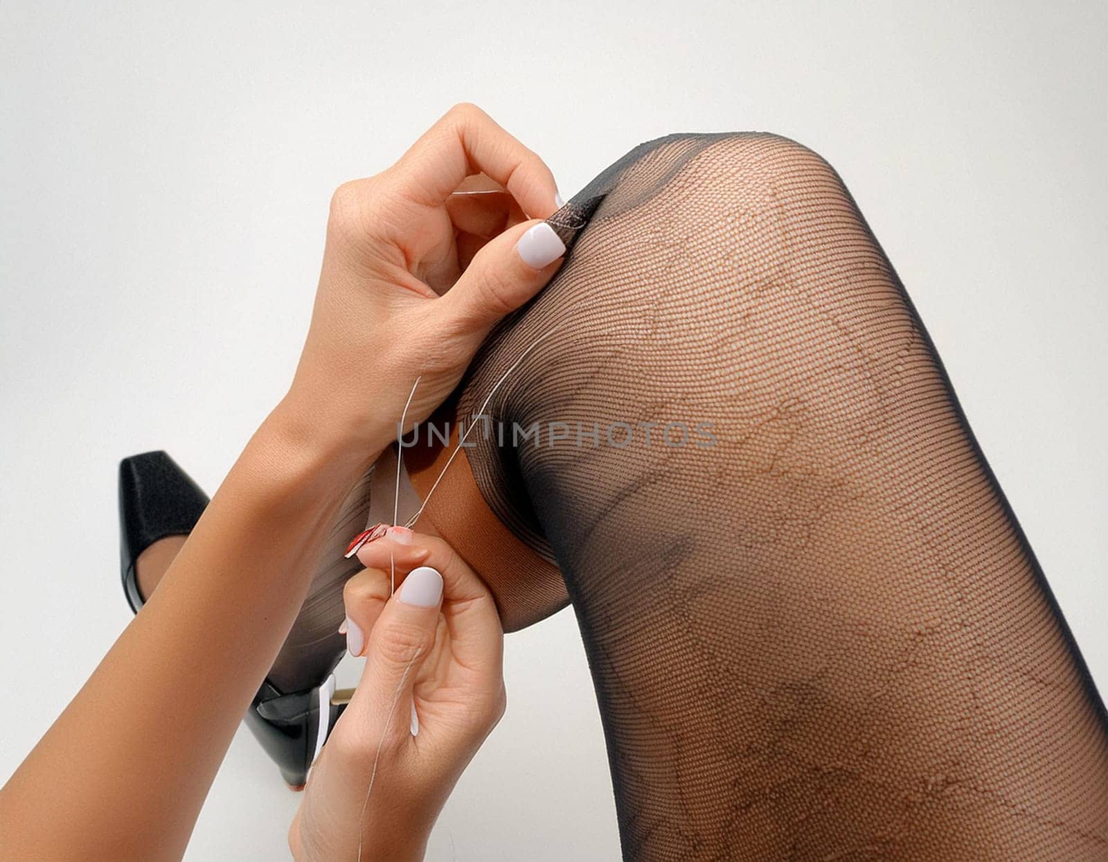 Female legs in black stockings on white background.