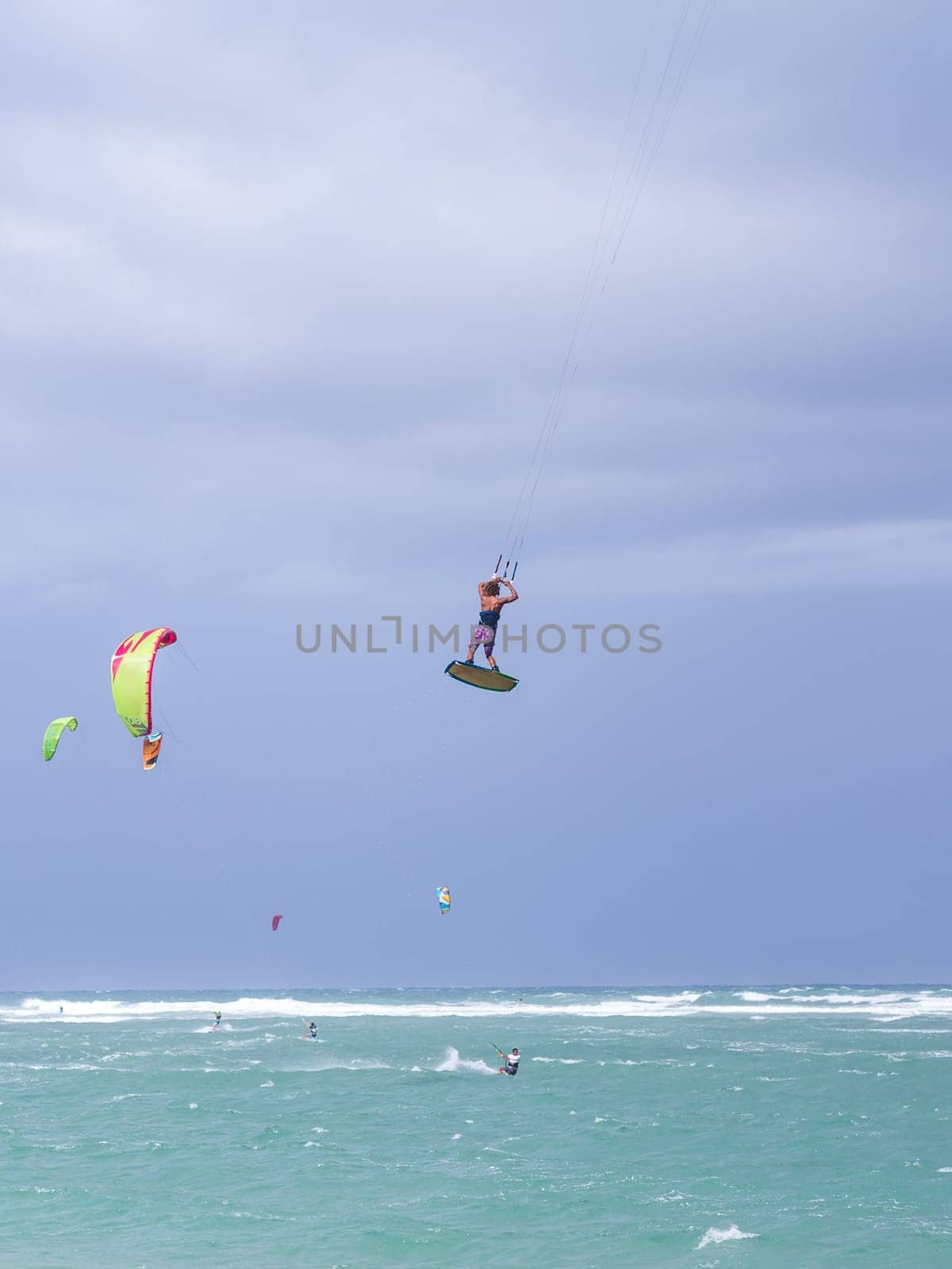 Kiteboarding. Fun in the ocean. Extreme Sport Kitesurfing. Kitesurfer jumping high in the air performing triks during kitesurfing session