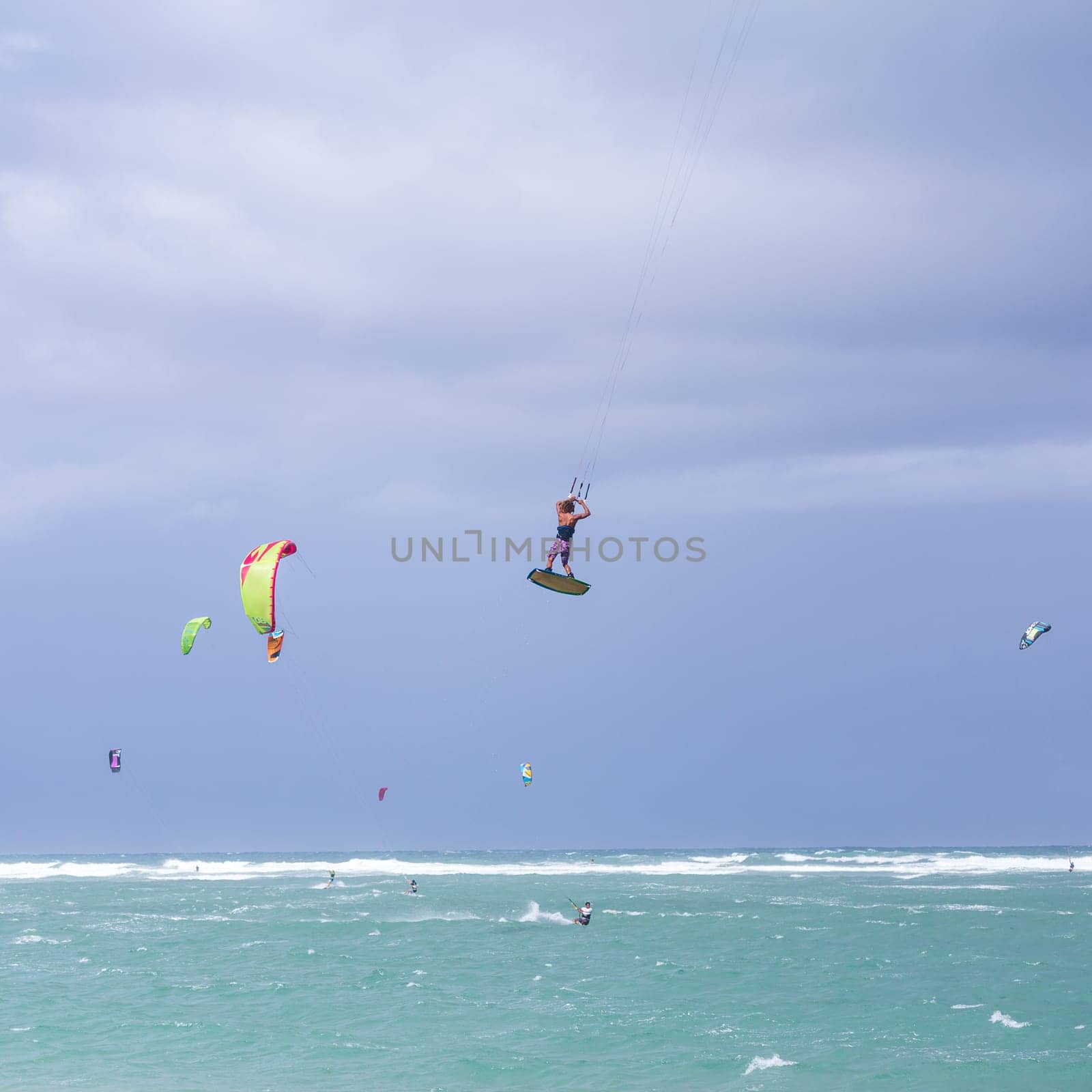 Kiteboarding. Fun in the ocean. Extreme Sport Kitesurfing. Kitesurfer jumping high in the air performing triks during kitesurfing session