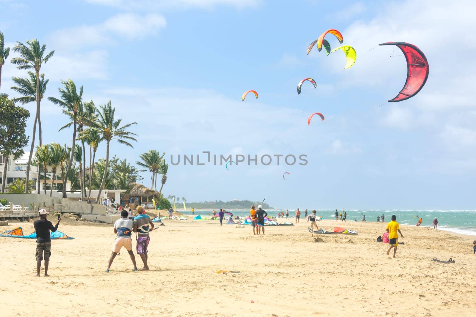 Crowd of active sporty people enjoying kitesurfing holidays and activities on perfect sunny day on Cabarete tropical sandy beach in Dominican Republic
