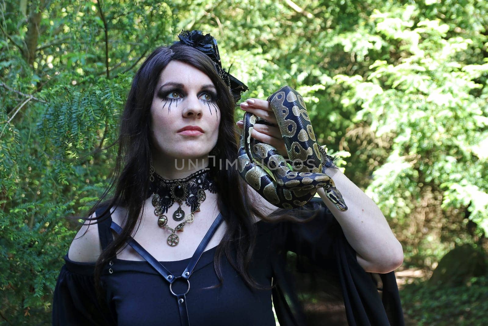 A woman dressed as a witch holds a snake in her hand