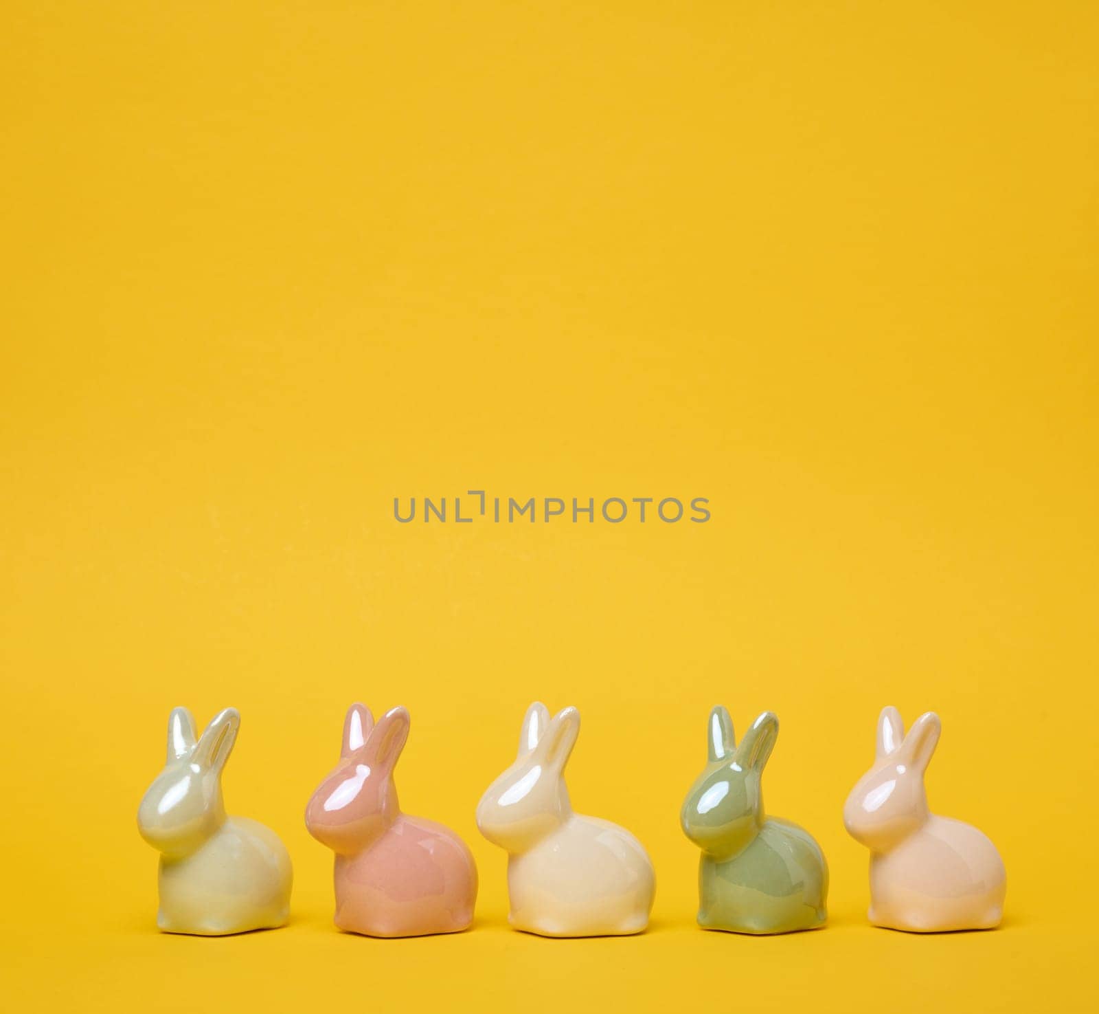 Ceramic decorative bunnies on a yellow background, festive Easter background