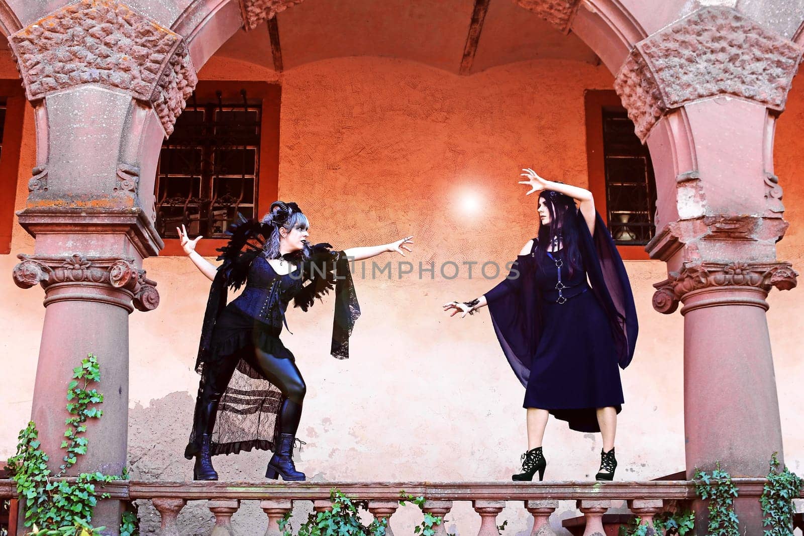 Two women dressed as witches fight with a ball of light