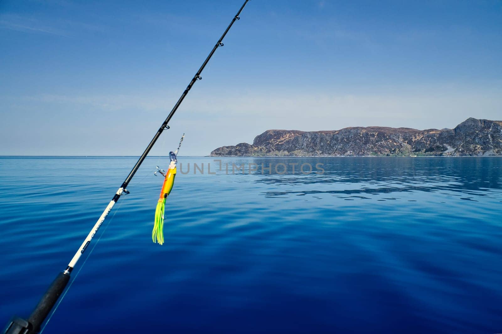 Fishing rod in front of the West Cape in the Norwegian fjord landscape. Crystal clear water in Scandinavia