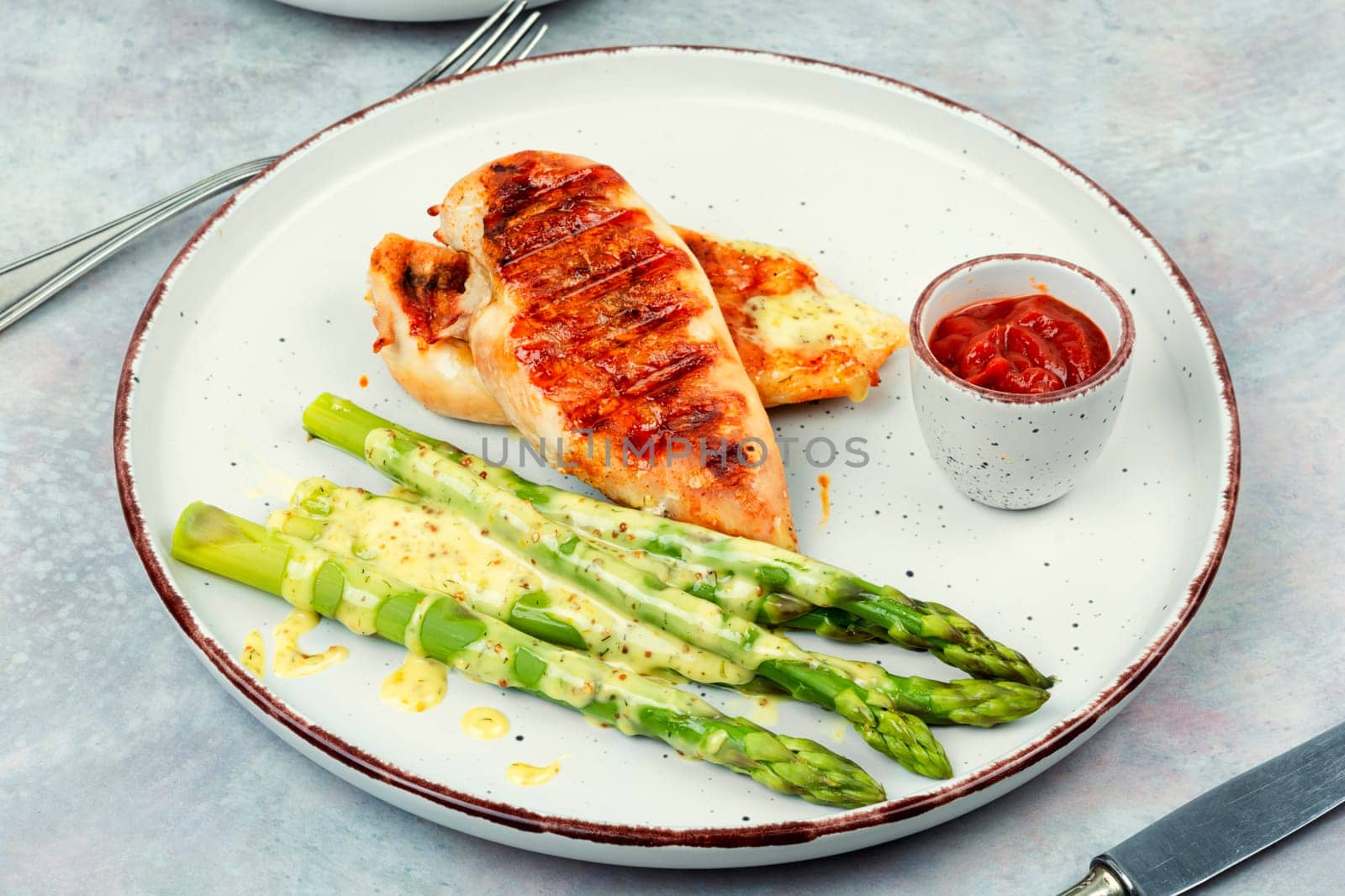Roasted or grilled chicken breasts with green asparagus. Healthy eating concept.