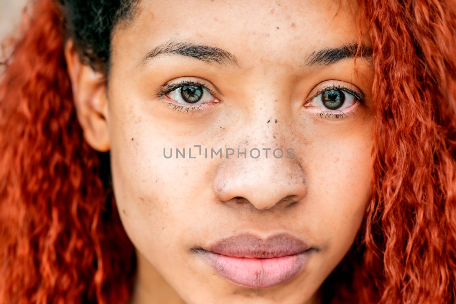 Black teenage girl with red dyed hair and afro hairstyle.