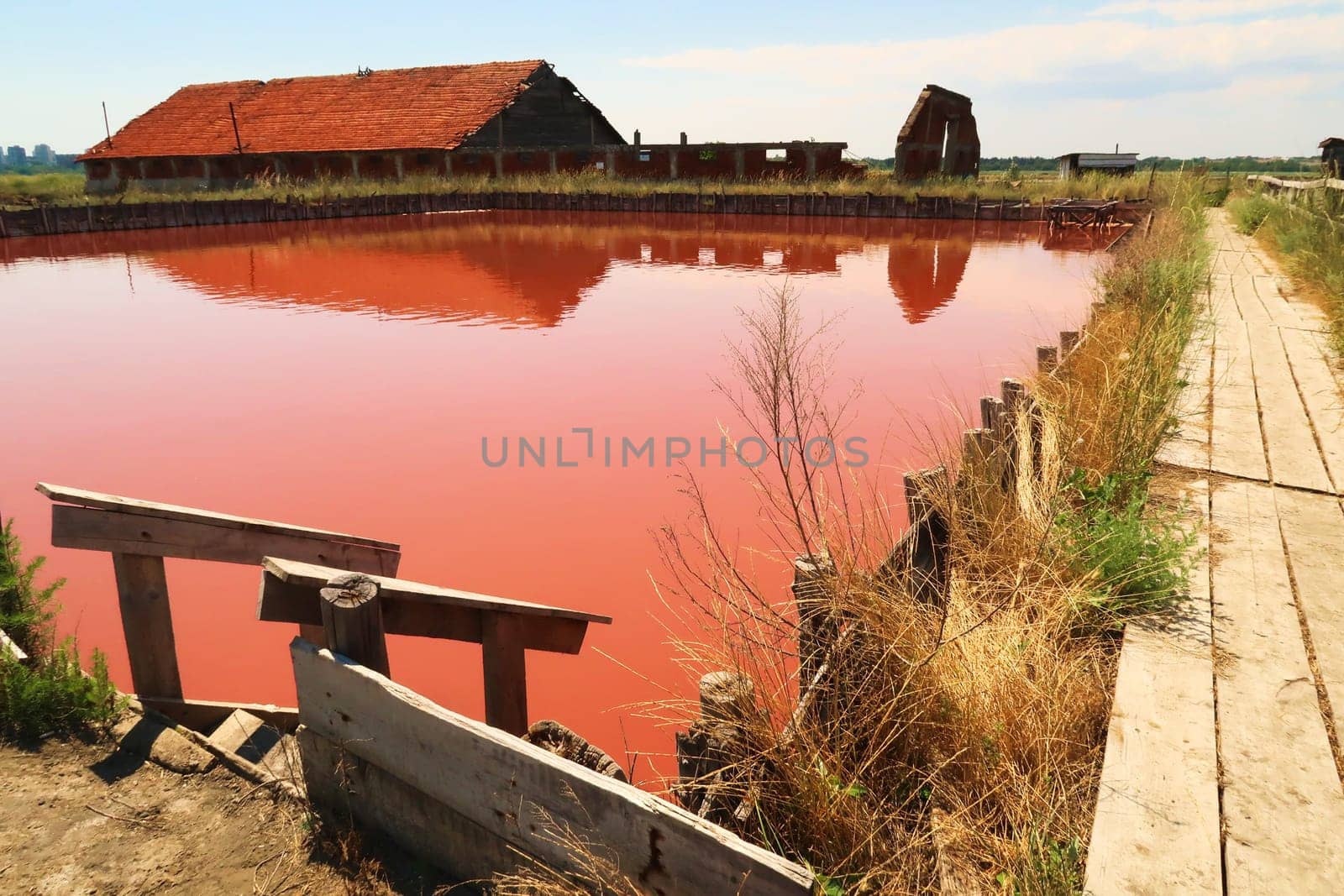Wooden board walk and stairs leading into the main bathing, swimming pool with its intense pink color at the Burgas Salt Pans, Lake Atanasovsko, Atanasovo, Burgas, Bourgas, Bulgaria 2022