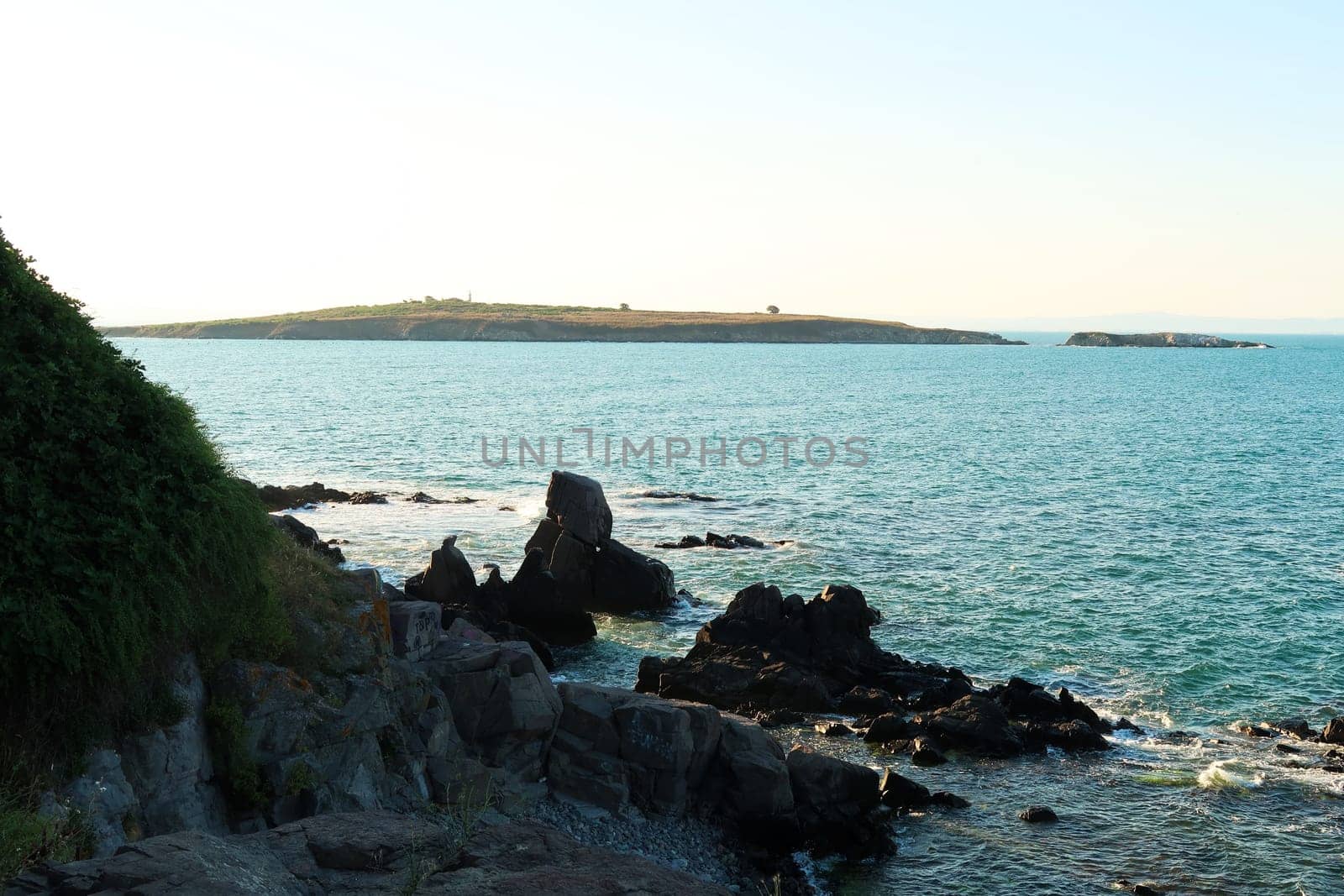 View from a beach in the old town of Sozopol, Sosopol onto St. Saint Ivan Island, black rocks in the foreground, Bulgaria 2022