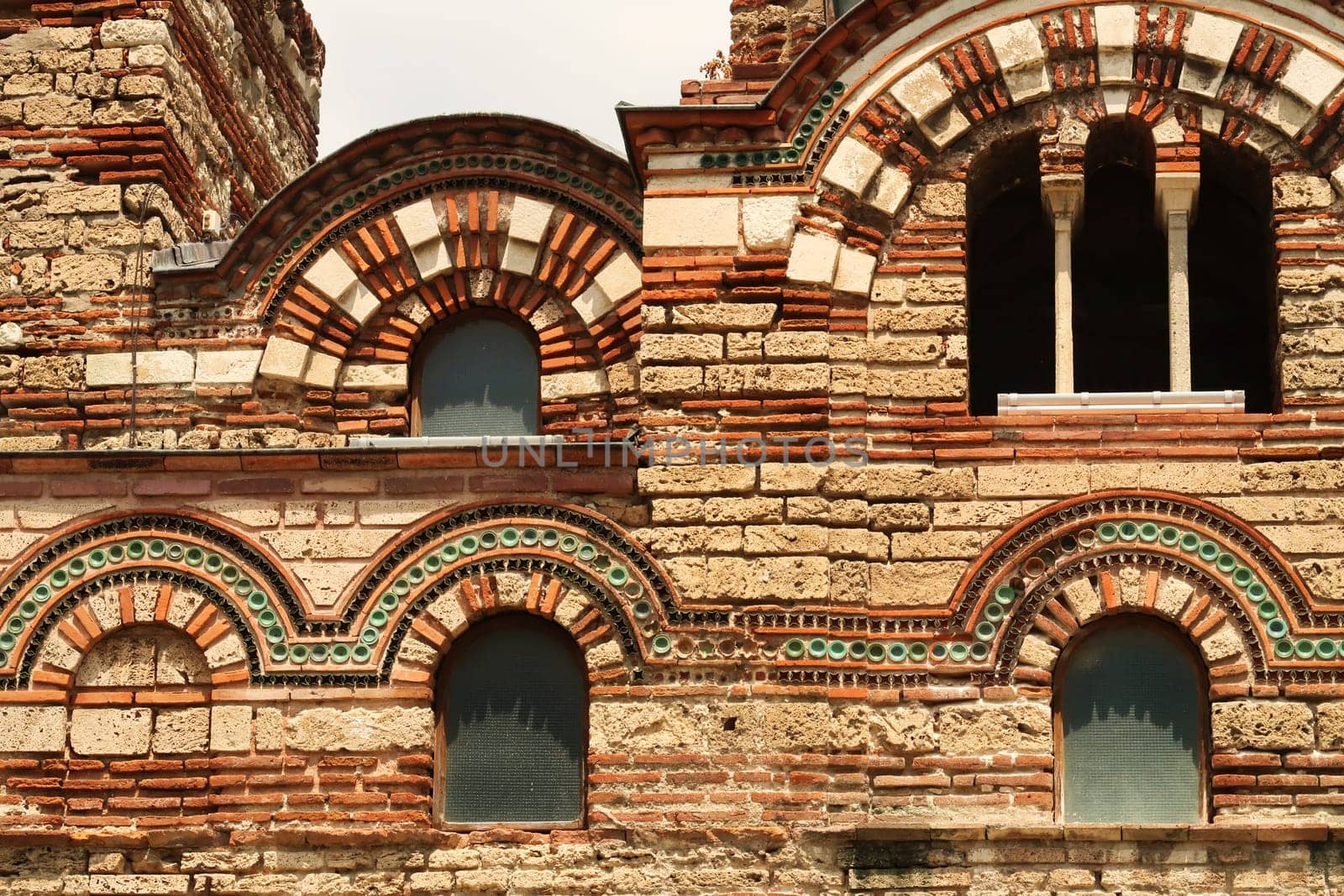 The beautiful facade of the Church of Christ Pantocrator in the old town of Nessebar, Nesebar, elaborate patterns out of bricks and colorful tiles around the windows, Bulgaria 2022