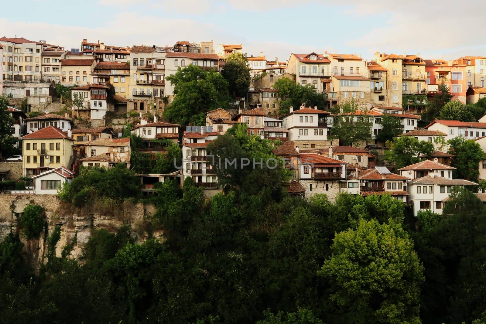 Beautiful view onto one of the neighborhoods of the old town of Veliko Tarnovo, rising above a dense forest, Veliko Tarnovo, Bulgaria 2022