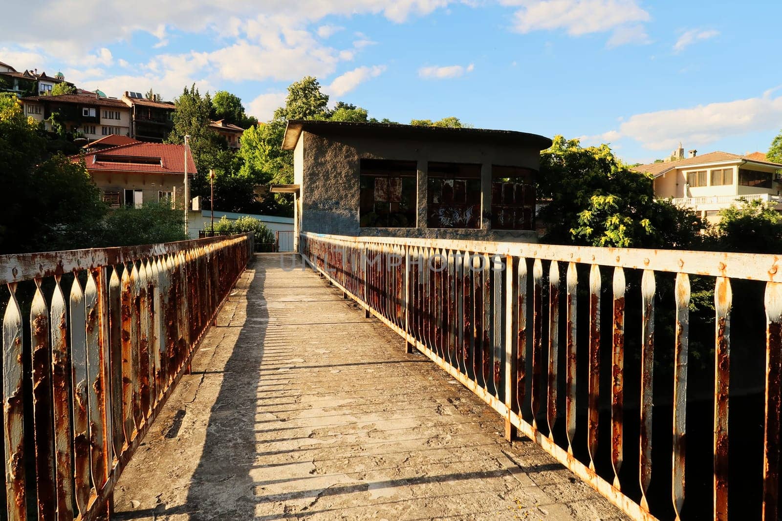 Walking over an abandoned dam on the Yantra River, rusted, rusty railings, handrails, rails on both sides of the concrete bridge, Veliko Tarnovo, Bulgaria 2022