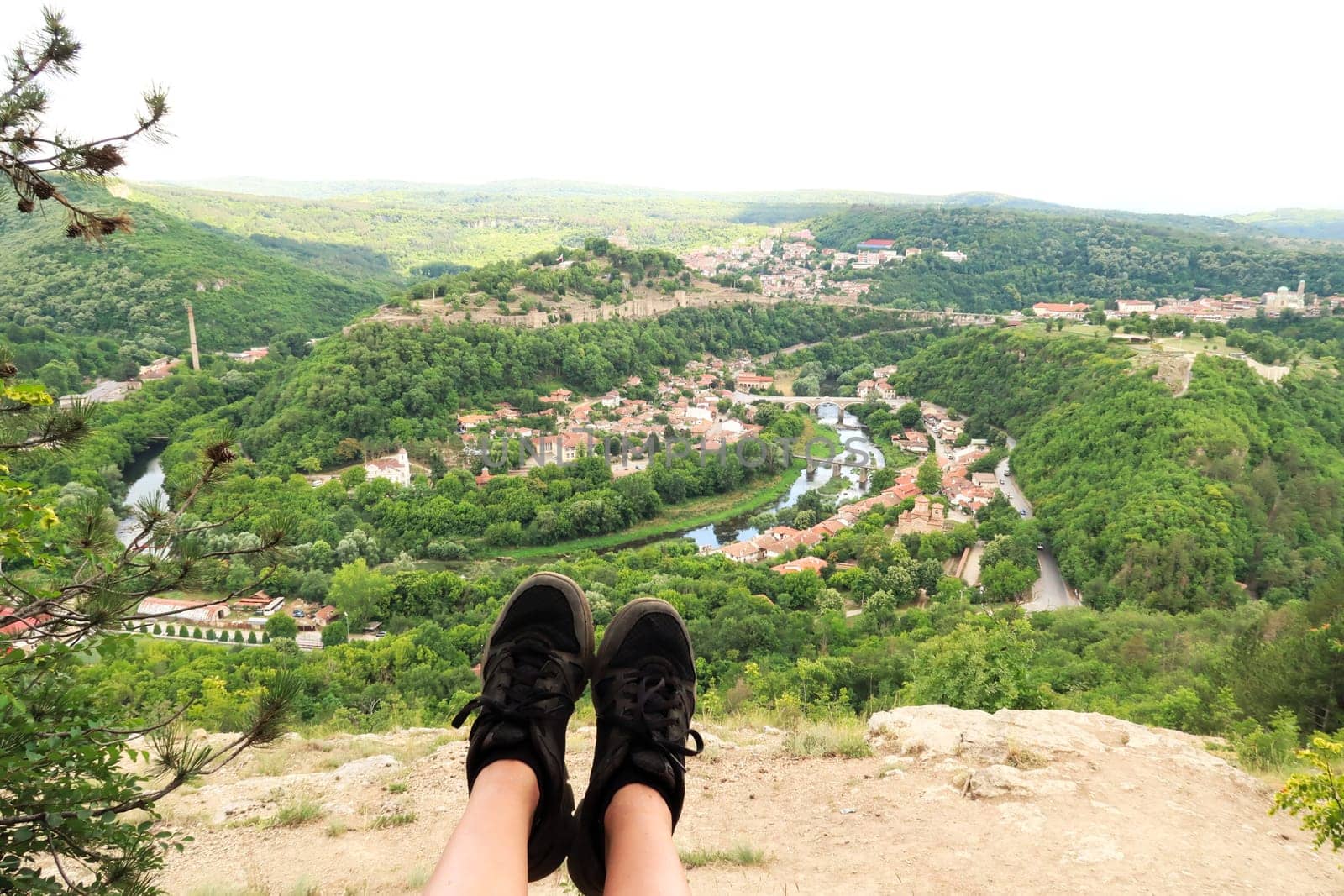 Sitting on the love swing on Garga Bair, black shoes in front of a scenic view over the city of Veliko Tarnovo and the lush dense forest that surrounds it, Veliko Tarnovo, Bulgaria 2022