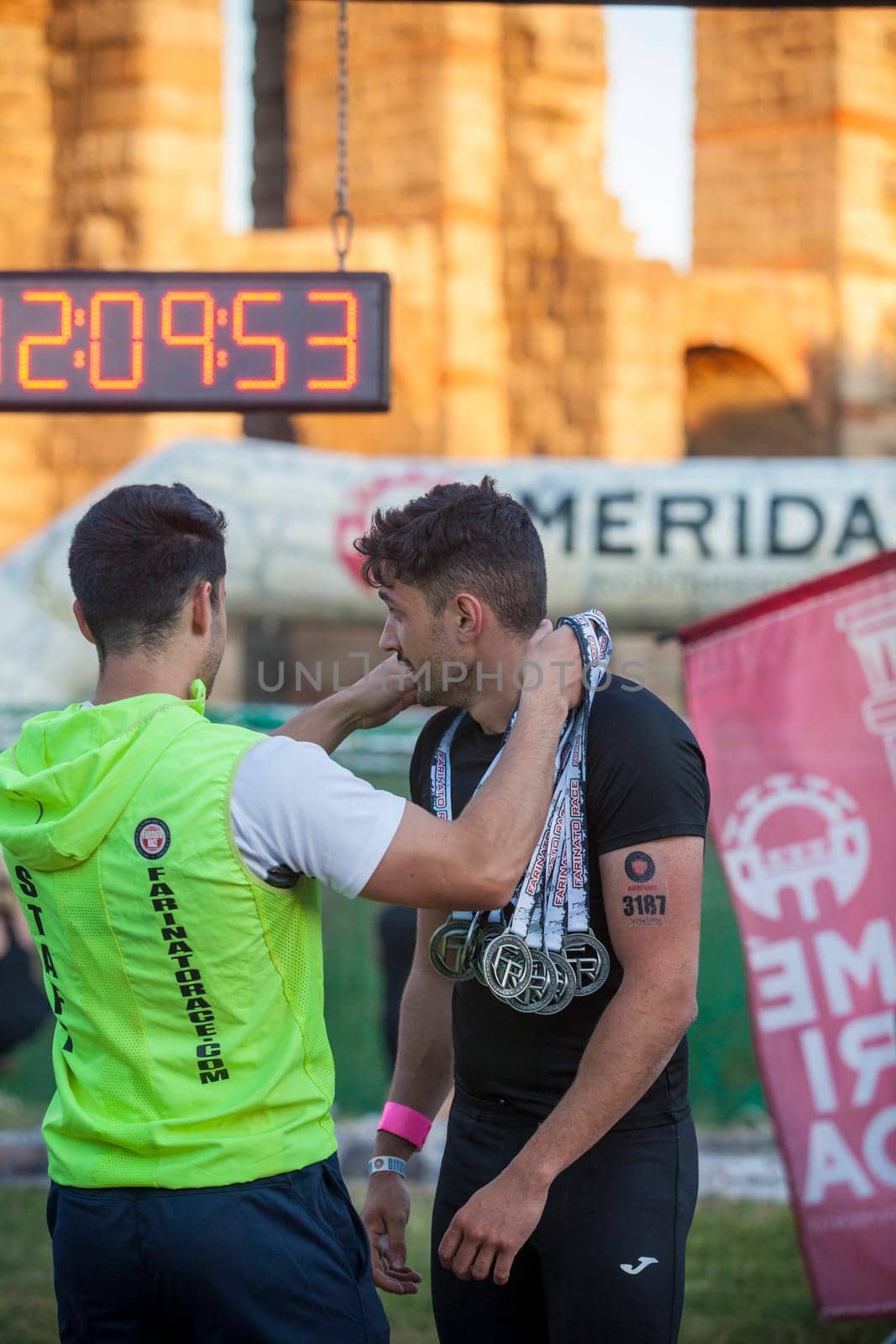 Merida, Spain - May 18th, 2024: FarinatoRace Merida 2024. Assistant hangs a medal on a participant at the finish line
