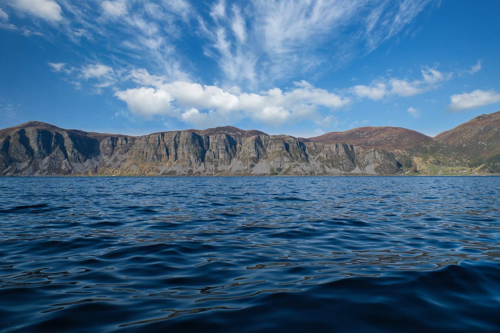 Norwegian fjord landscape. View of mountains with rugged vegetation. Crystal clear water in the foreground. Landscape from Scandinavia