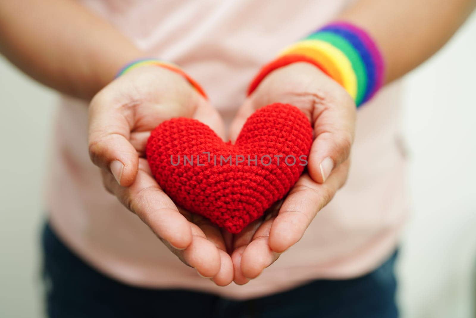 Asian woman holding red heart with rainbow flag, LGBT symbol rights and gender equality, LGBT Pride Month in June.