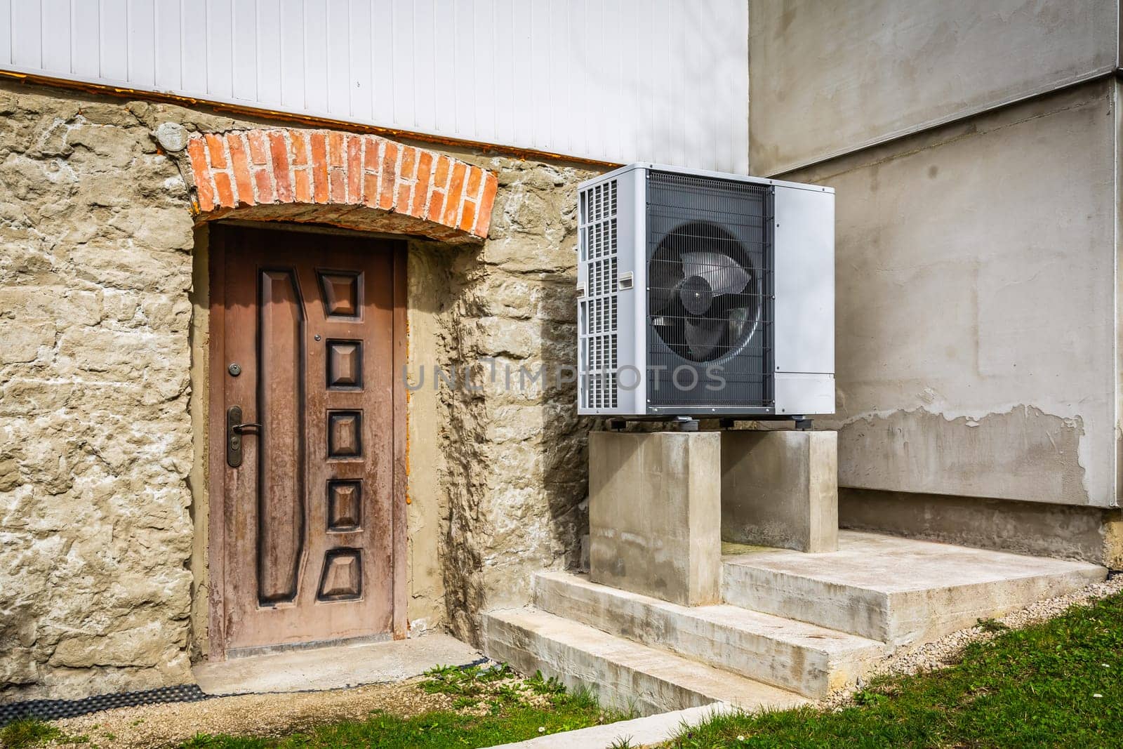 Air source heat pump installed outside of old renovated house, green renewable energy concept of heat pump