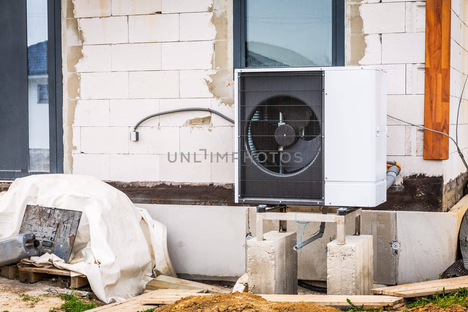 Air source heat pump installed outside of new and modern house under construction, green renewable energy concept of heat pump