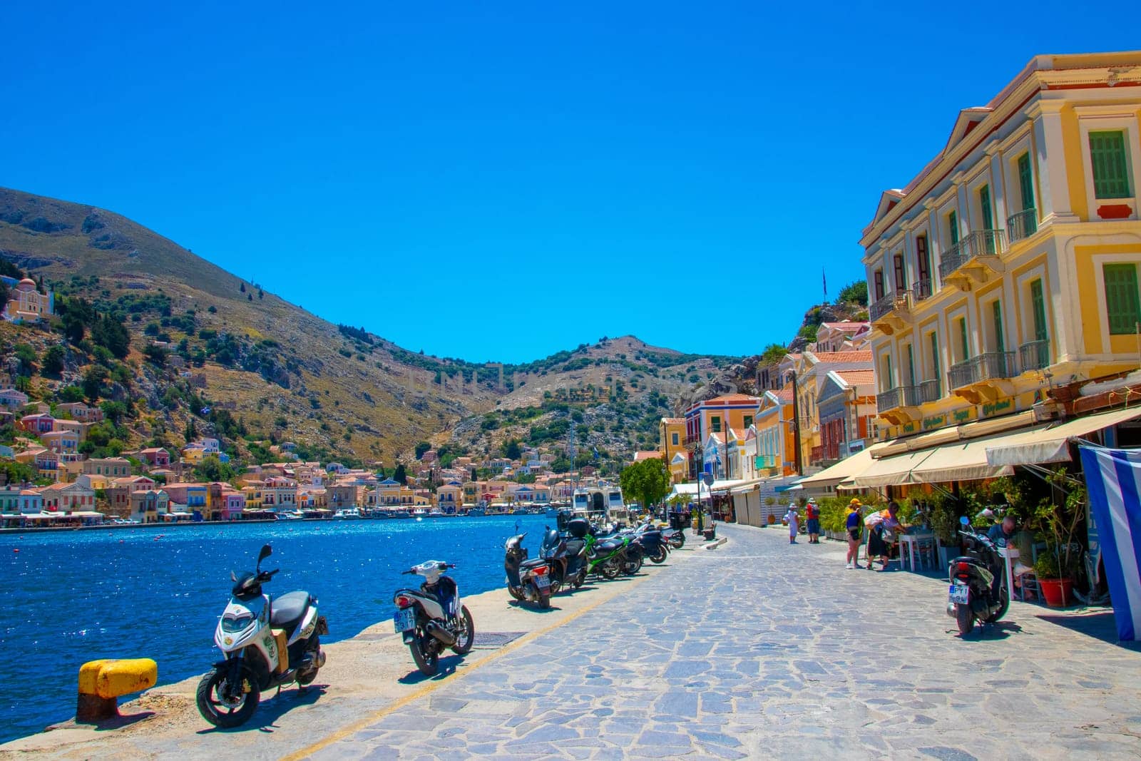 SYMI, Greece - Jun 03, 2021. The harbour of Symi town with the districts of Chorio and Gialos is one of the most beautiful and romantic in the whole Aegean. Colourful mansions stretch up the steep slopes.